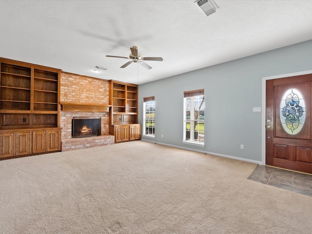 unfurnished living room featuring light carpet, a textured ceiling, a brick fireplace, and visible vents