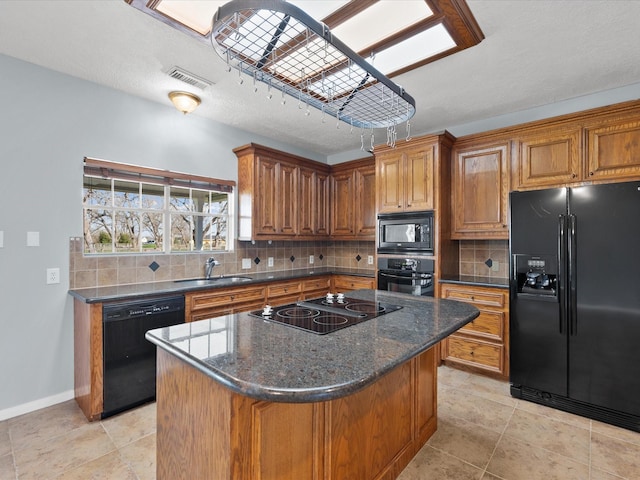 kitchen with tasteful backsplash, a kitchen island, brown cabinets, black appliances, and a sink