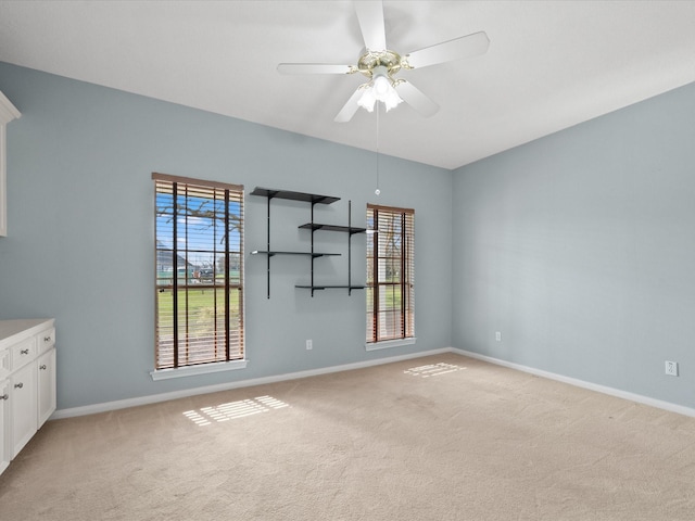 spare room featuring ceiling fan, baseboards, and light colored carpet