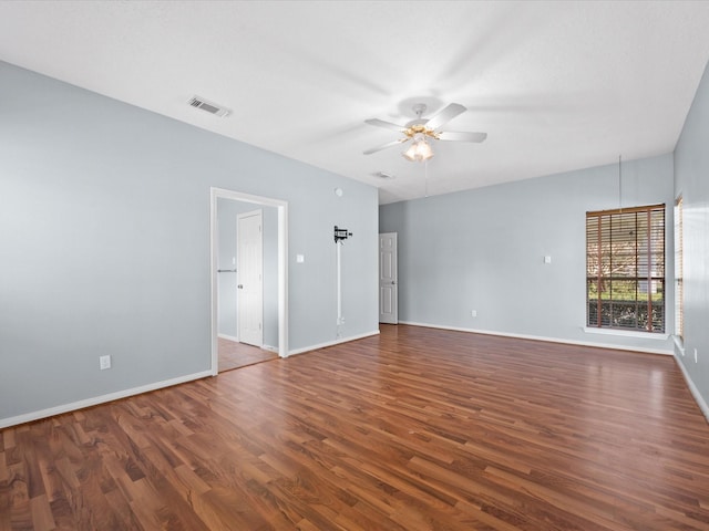 empty room featuring baseboards, ceiling fan, visible vents, and dark wood-style flooring