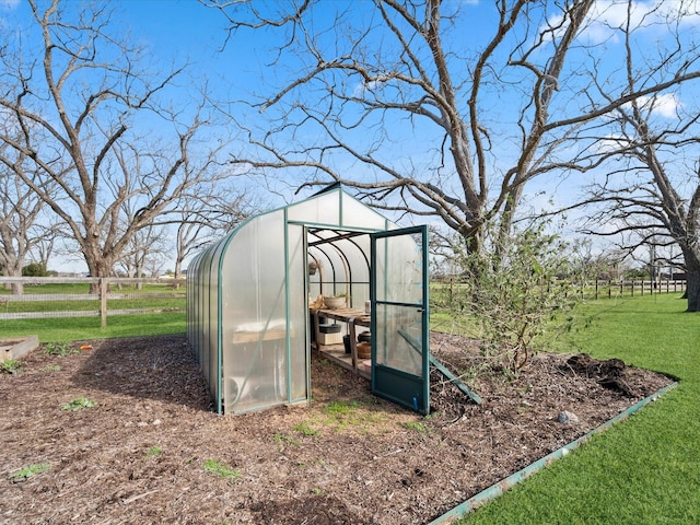 view of greenhouse featuring a yard, fence, and a rural view