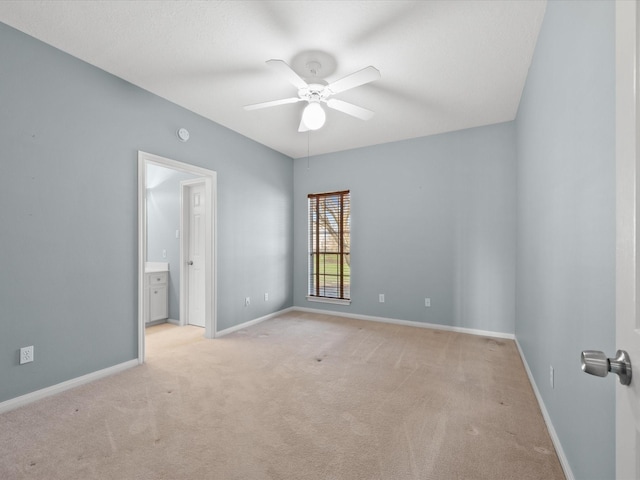 empty room featuring a ceiling fan, light carpet, and baseboards