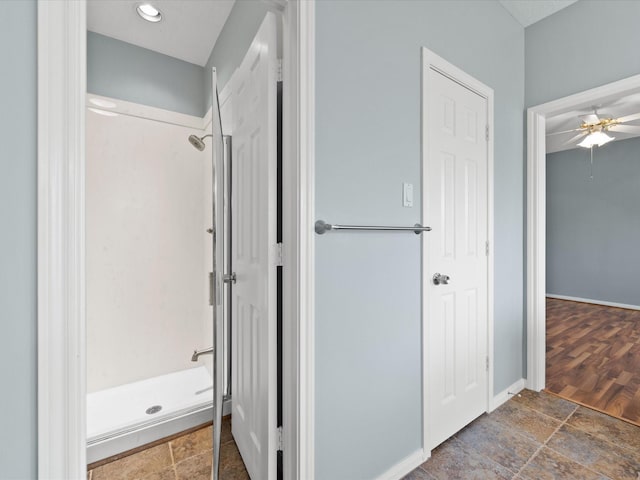 full bathroom featuring stone finish flooring, a shower stall, and baseboards