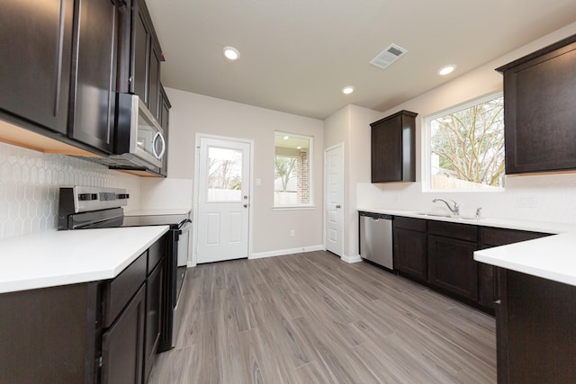 kitchen featuring visible vents, appliances with stainless steel finishes, dark brown cabinets, a healthy amount of sunlight, and a sink