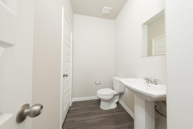 bathroom with toilet, a sink, baseboards, and wood finished floors