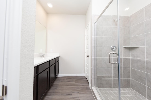 bathroom with recessed lighting, a stall shower, vanity, wood finished floors, and baseboards