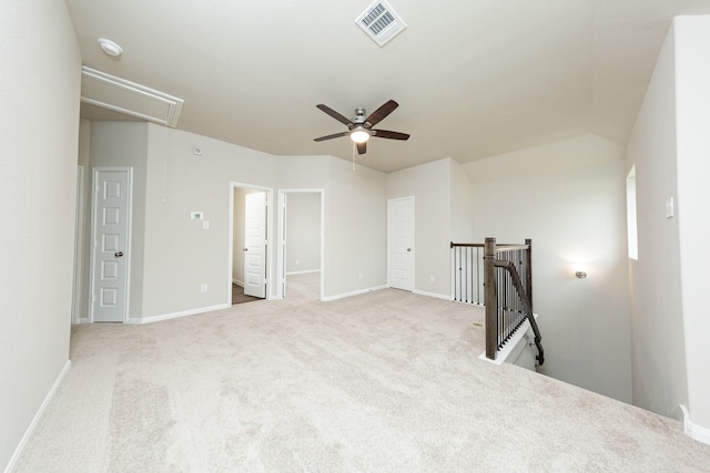 carpeted empty room with attic access, visible vents, ceiling fan, and baseboards