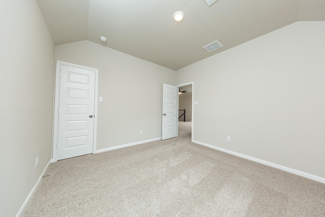 spare room with vaulted ceiling, light carpet, visible vents, and baseboards