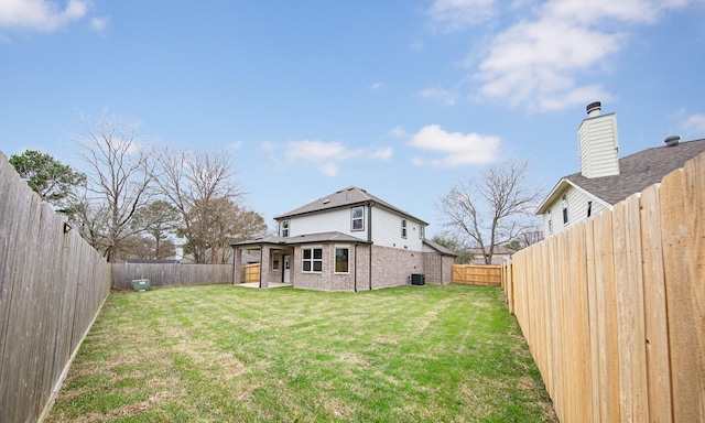 rear view of property with brick siding, a lawn, and a fenced backyard