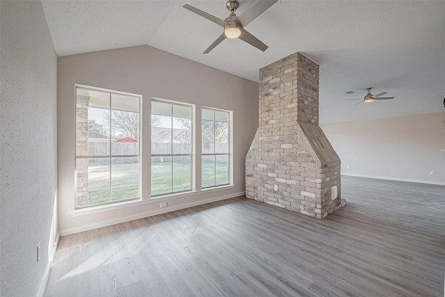 unfurnished living room featuring hardwood / wood-style flooring, plenty of natural light, lofted ceiling, and a textured ceiling