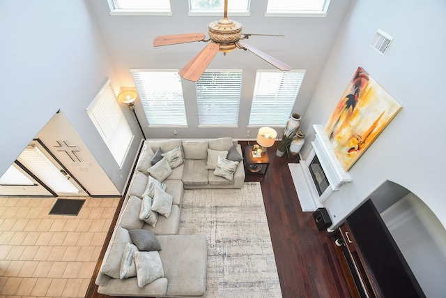 living room featuring hardwood / wood-style flooring, ceiling fan, plenty of natural light, and a high ceiling
