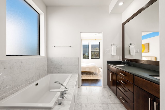 bathroom with a relaxing tiled tub, tile patterned floors, and vanity