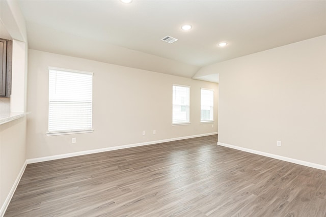 empty room with wood-type flooring and vaulted ceiling