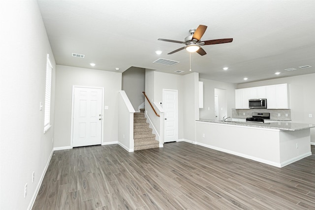 kitchen featuring sink, white cabinets, kitchen peninsula, stainless steel appliances, and light stone countertops