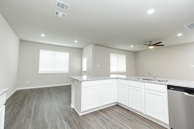 kitchen featuring light stone counters, stainless steel dishwasher, sink, and white cabinets