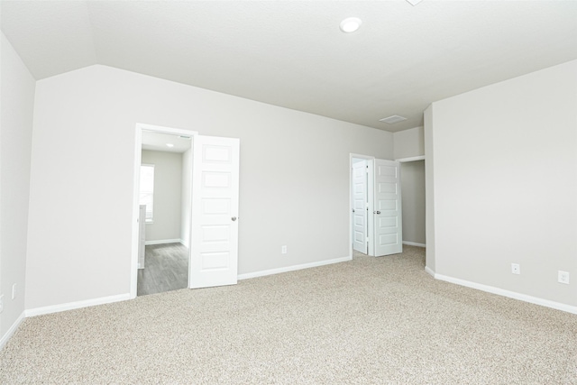 unfurnished bedroom with lofted ceiling and carpet