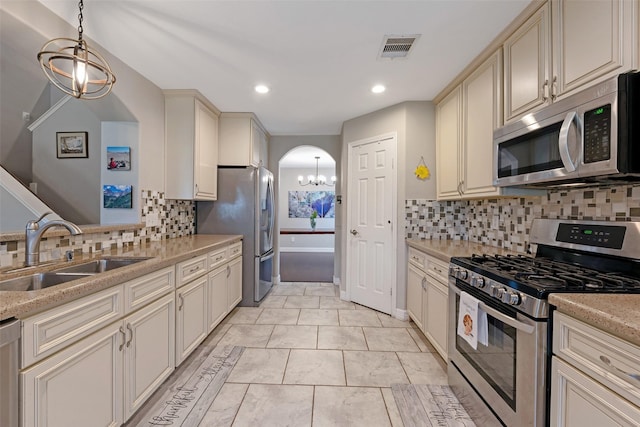 kitchen with decorative light fixtures, sink, decorative backsplash, stainless steel appliances, and cream cabinetry