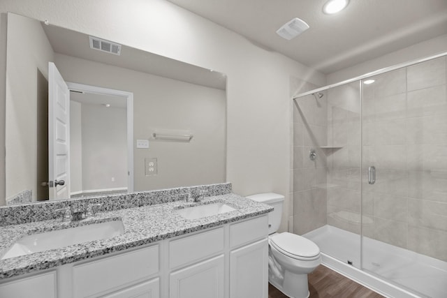 bathroom with vanity, a shower with shower door, hardwood / wood-style floors, and toilet