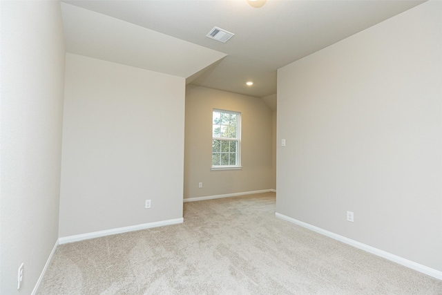 spare room with lofted ceiling and light colored carpet