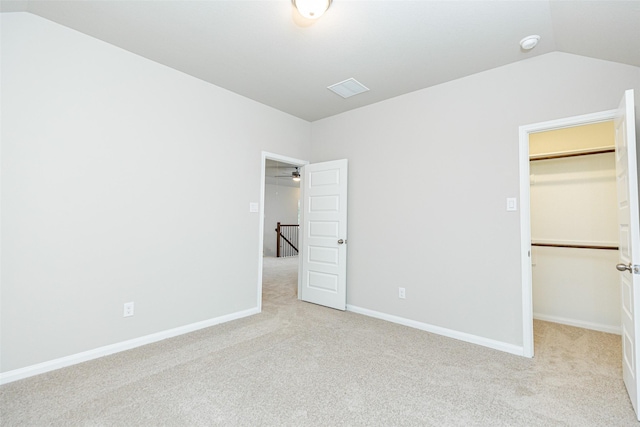 unfurnished bedroom featuring vaulted ceiling, a spacious closet, light colored carpet, and a closet