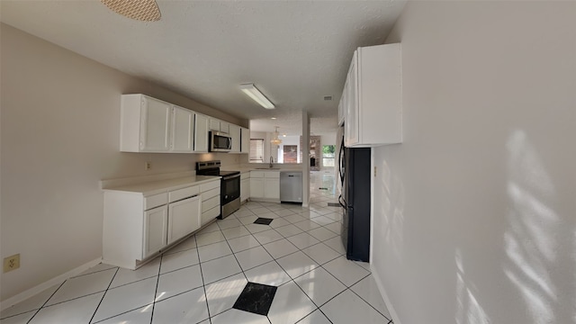 kitchen featuring stainless steel appliances, light tile patterned flooring, sink, and white cabinets