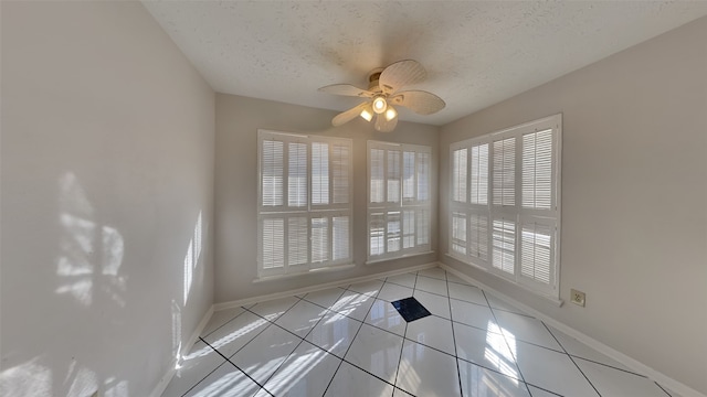 spare room featuring ceiling fan, light tile patterned floors, and a textured ceiling