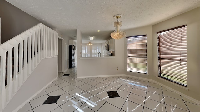 tiled spare room featuring sink, a chandelier, and a textured ceiling