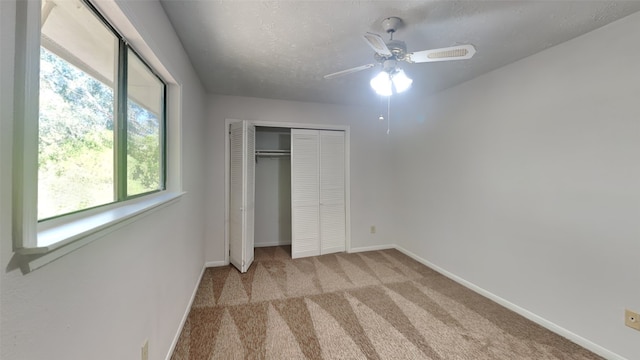 unfurnished bedroom with light colored carpet, a textured ceiling, and ceiling fan