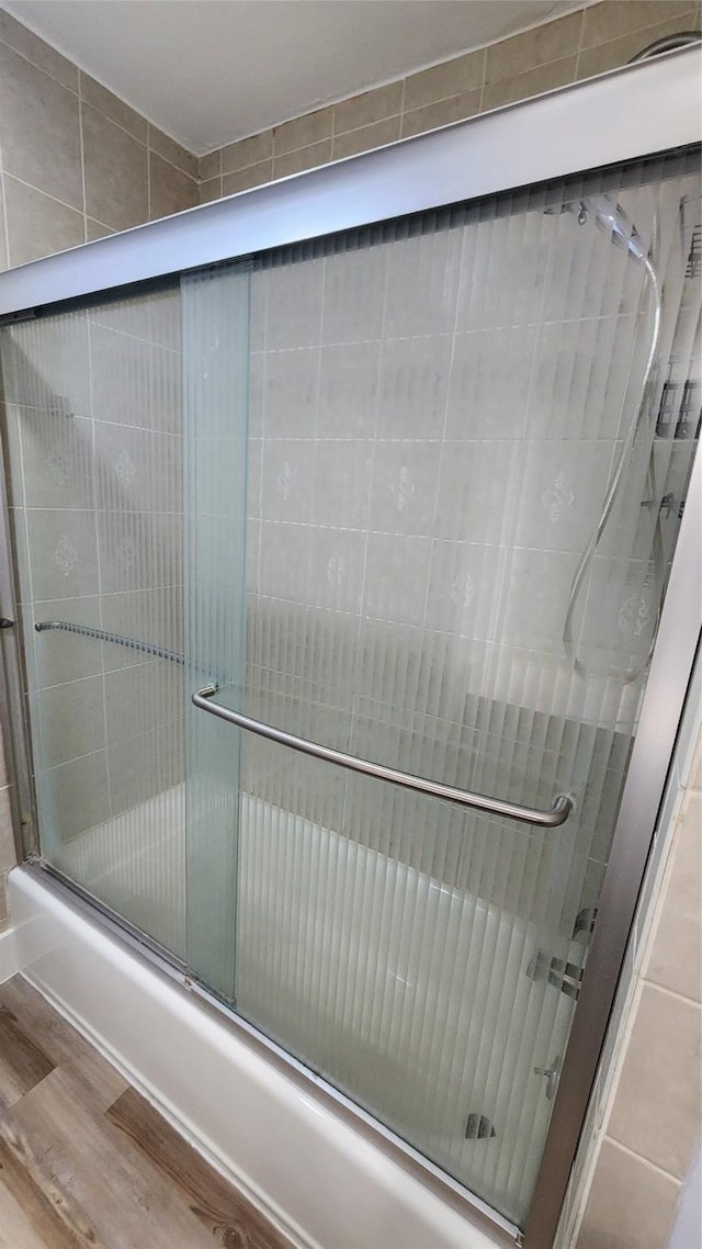 bathroom with enclosed tub / shower combo and wood-type flooring