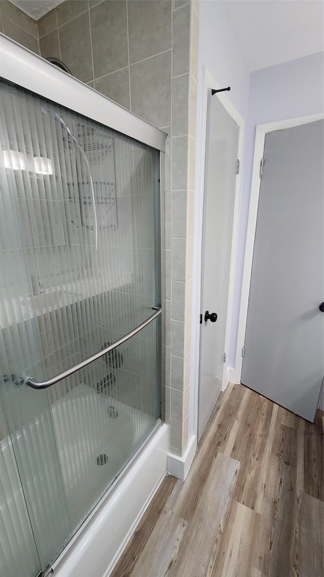 bathroom featuring hardwood / wood-style flooring and enclosed tub / shower combo