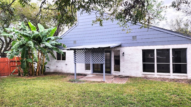 rear view of property with a patio and a lawn