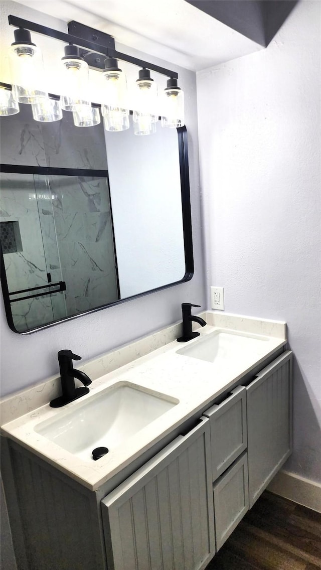 bathroom with wood-type flooring, vanity, and a tile shower