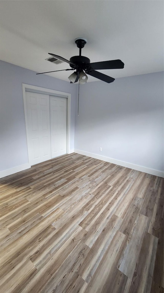 unfurnished bedroom featuring light hardwood / wood-style floors, ceiling fan, and a closet