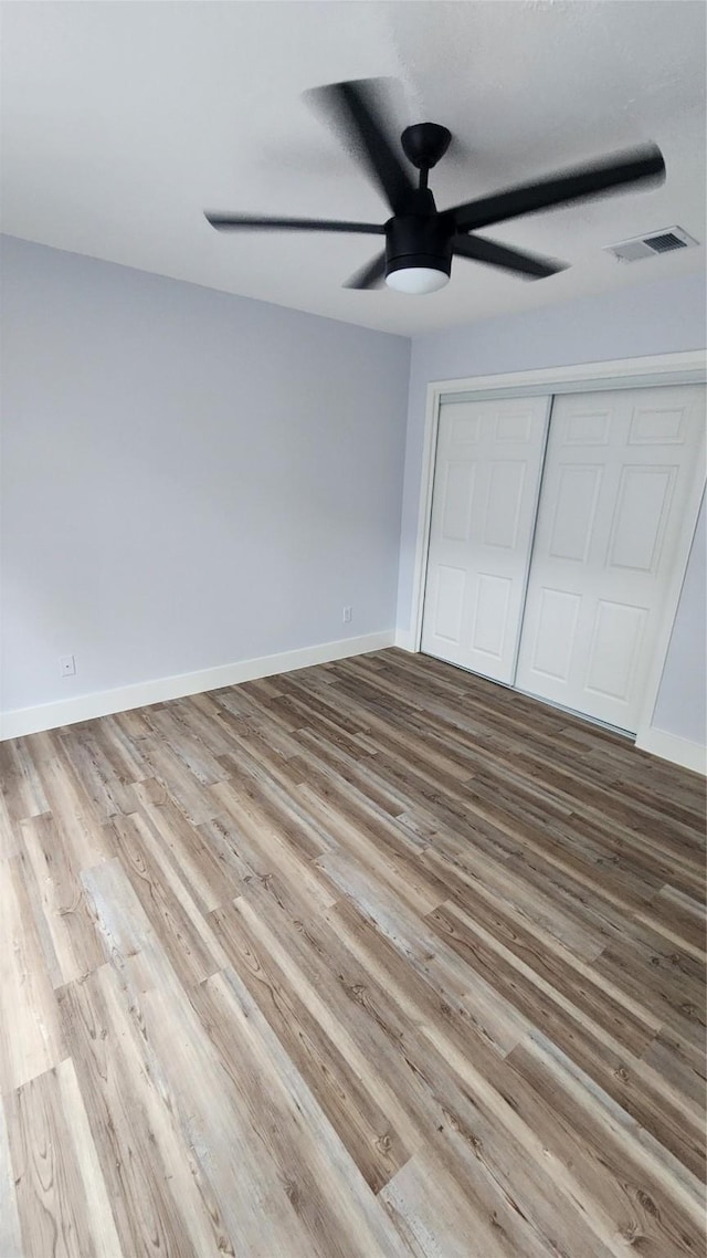 unfurnished bedroom with light hardwood / wood-style flooring, a closet, and ceiling fan