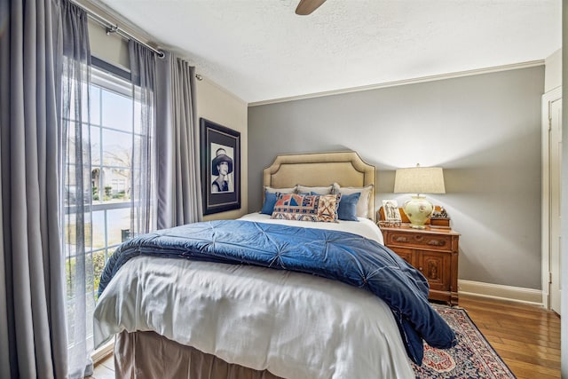 bedroom with hardwood / wood-style flooring, ceiling fan, crown molding, and multiple windows