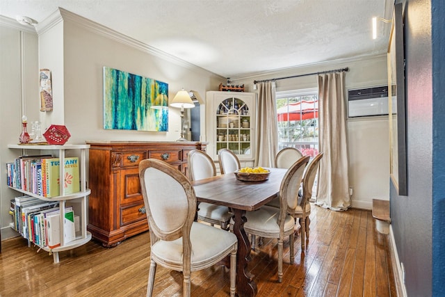 dining area featuring crown molding, an AC wall unit, light hardwood / wood-style flooring, and a textured ceiling