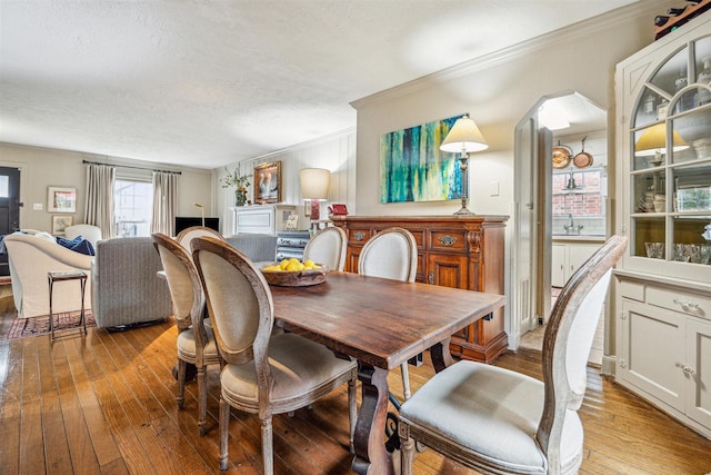 dining area with ornamental molding, sink, a textured ceiling, and light hardwood / wood-style flooring