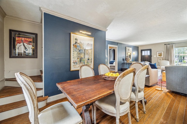 dining room featuring ornamental molding, hardwood / wood-style floors, and a textured ceiling