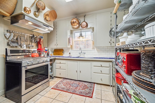 kitchen with white cabinetry, gas range, light tile patterned flooring, and extractor fan