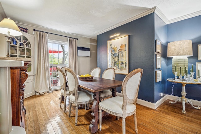 dining area with crown molding, a wall mounted air conditioner, a textured ceiling, and light wood-type flooring