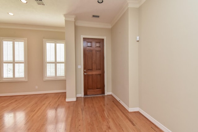 foyer entrance with ornamental molding, light hardwood / wood-style floors, and decorative columns