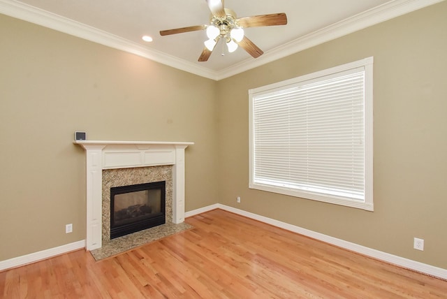 unfurnished living room featuring crown molding, ceiling fan, a premium fireplace, and light hardwood / wood-style flooring