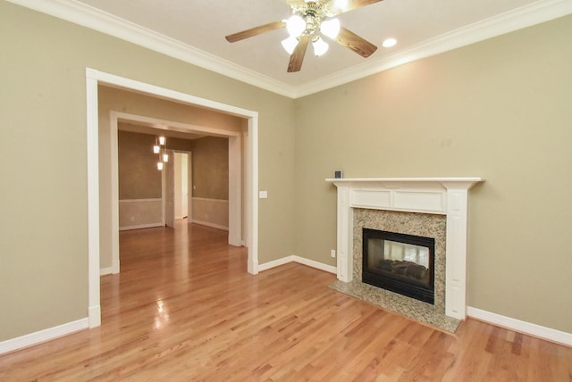 unfurnished living room with ceiling fan, ornamental molding, a fireplace, and light wood-type flooring