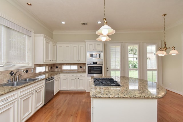 kitchen featuring stainless steel appliances, a kitchen island, sink, and pendant lighting