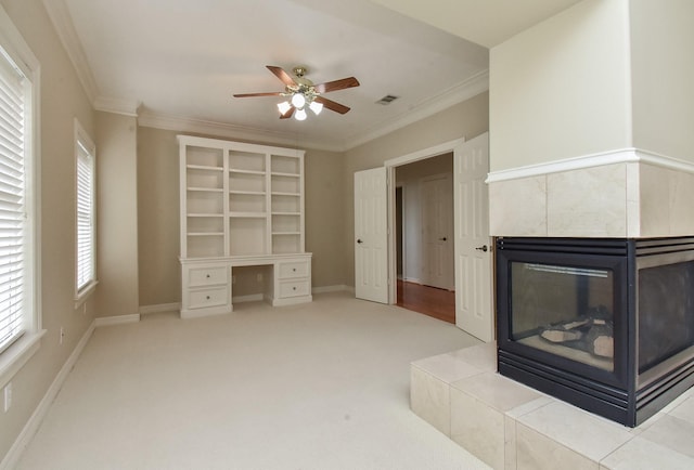 unfurnished living room featuring light carpet, crown molding, ceiling fan, and a tiled fireplace