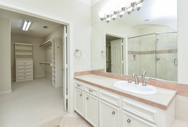 bathroom with a shower with door, vanity, tile patterned flooring, and crown molding