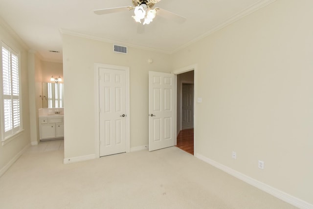 unfurnished bedroom featuring ornamental molding, connected bathroom, light carpet, and ceiling fan