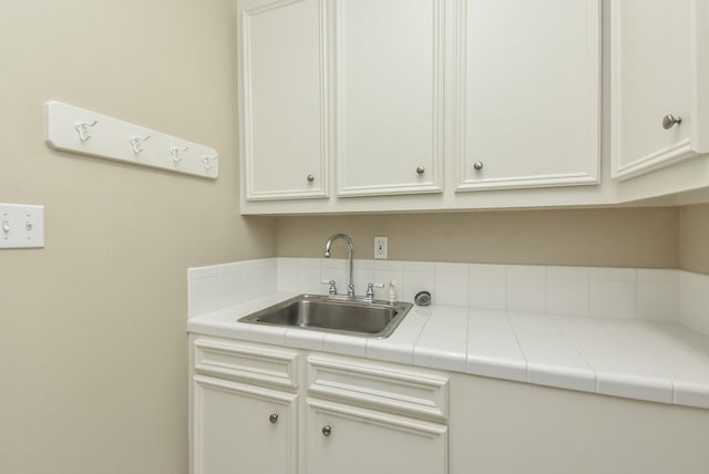 kitchen featuring sink, tile counters, and white cabinets