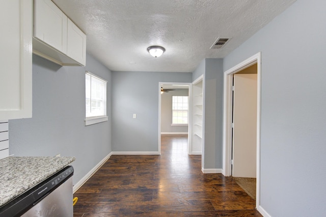 interior space with visible vents, baseboards, white cabinets, dishwasher, and dark wood finished floors