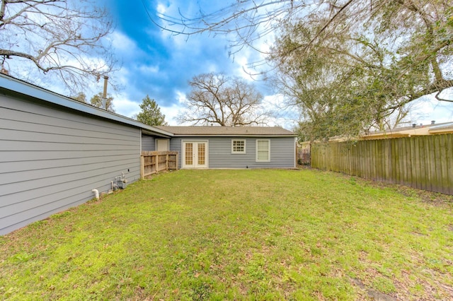 rear view of house with french doors, a lawn, and a fenced backyard